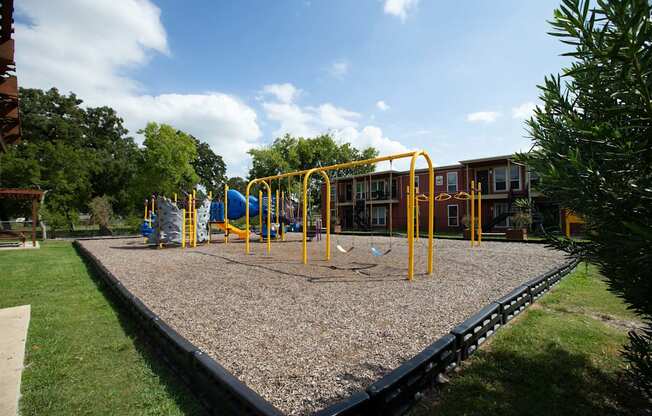 A playground with a swing set and a slide at Willow Creek Apartments, Houston