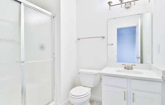 A white bathroom with a toilet, sink, and shower.
