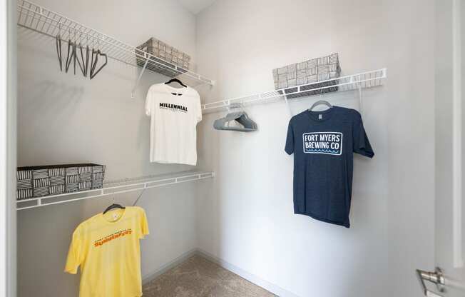 a walk in closet with shirts hanging on a rack and a shirt on the wall