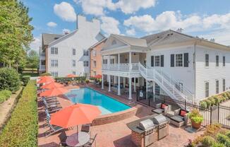 a swimming pool with umbrellas and chairs in front of a house at Sterling Manor, Virginia