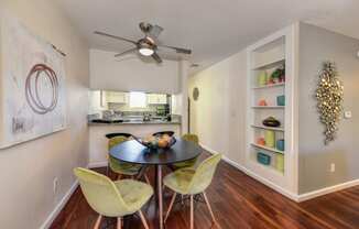 Dining Area with View of Kitchen, Built In Storage, Hardwood Inspired Floors, Yellow Chairs, Black Round Table and Ceiling Fan/Light at Monte Bello Apartments, California