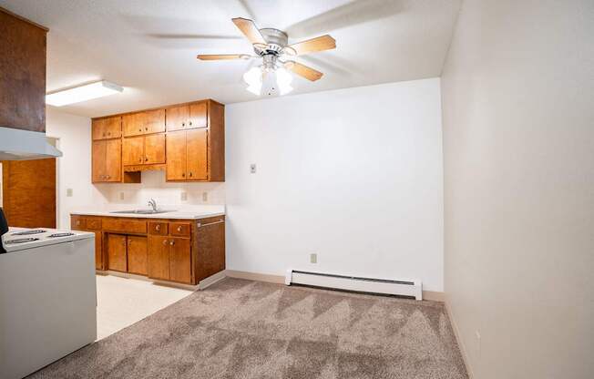 A room with a ceiling fan and a rug on the floor. Fargo, ND Islander Apartments