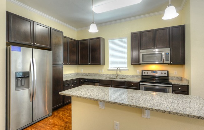 a kitchen with granite countertops and stainless steel appliances  at Alaqua, Jacksonville