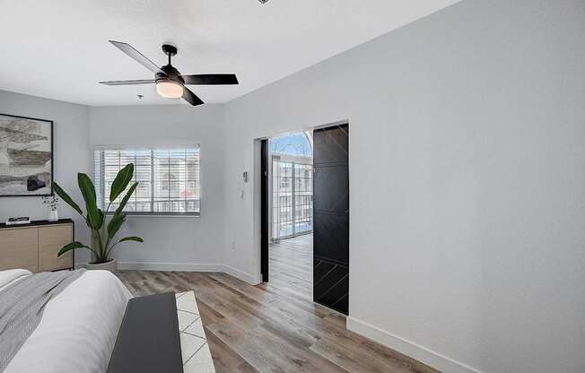 A room with a ceiling fan and a plant on the bed.