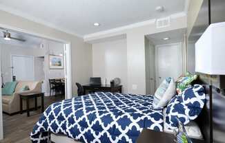 Fusion Orlando apartment bedroom with large open door to living area. Bedroom has large bed with blue and white duvet and desk nook.