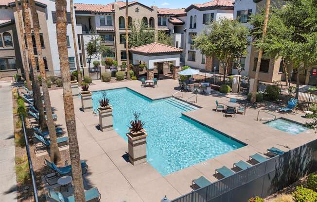 A large swimming pool surrounded by palm trees and lounge chairs.