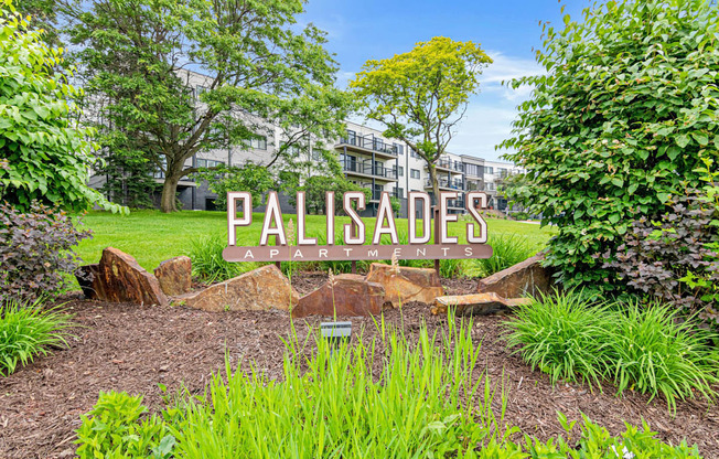A garden with a sign that says Palisades Apartments.