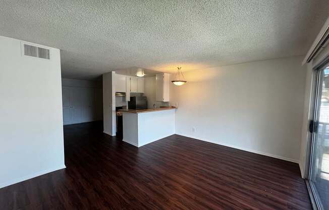 A room with wooden floors and a kitchenette.