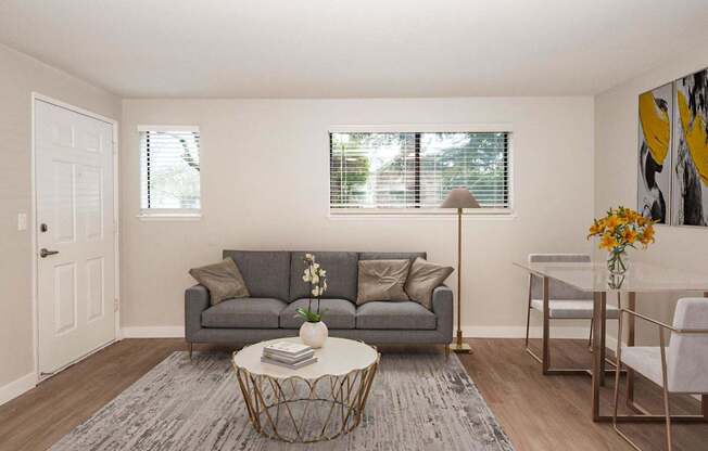 A living room with a grey couch, a white coffee table, and a grey rug.