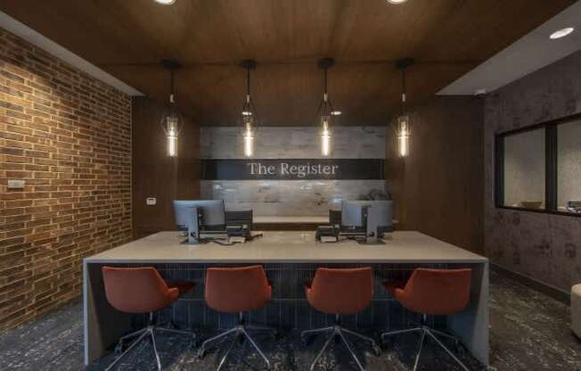 A conference room with a long table and chairs, a computer, and a sign that reads "The Register.".