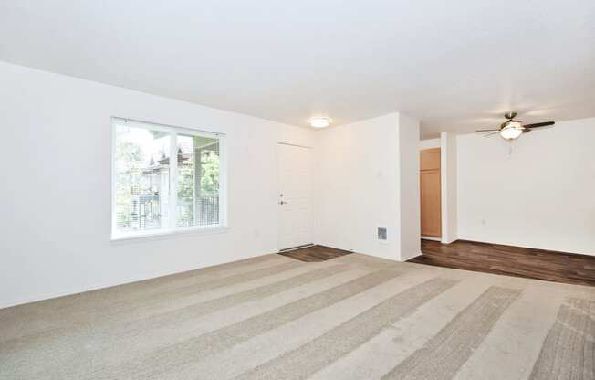 an empty living room with a window and a ceiling fan