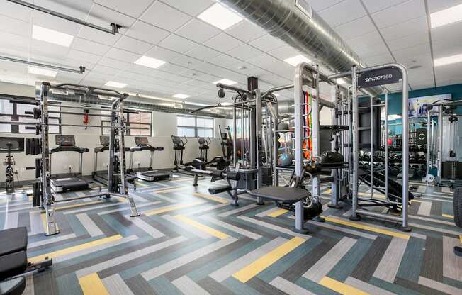 A gym with a variety of equipment including weights and treadmills.