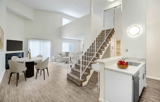 a living room and dining room with a staircase and a dining room table and chairs