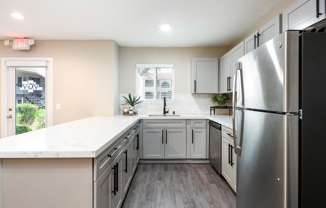 a kitchen with white cabinets and a stainless steel refrigerator