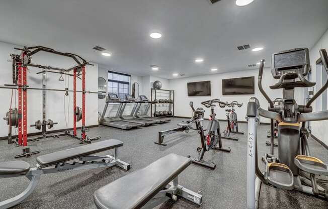 a gym with weights and cardio equipment in a room with a window