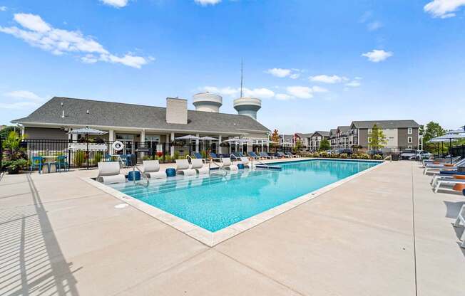 A large outdoor swimming pool with sun loungers and a building with a dome-shaped roof in the background.