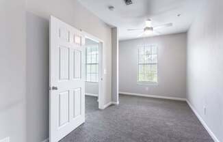 A room with a carpeted floor and a ceiling fan.