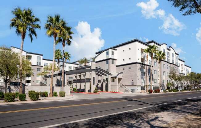 A street view of a residential area with apartment buildings and palm trees.