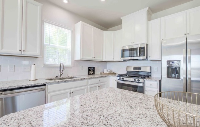 a white kitchen with granite counter tops and stainless steel appliances