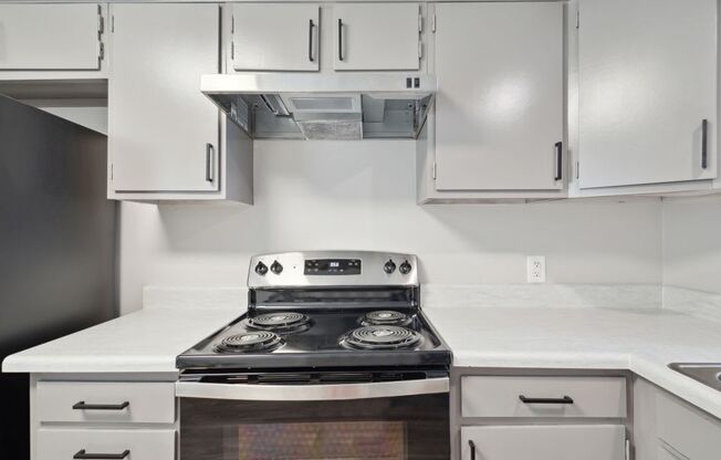 a kitchen with white cabinets and a stove top oven