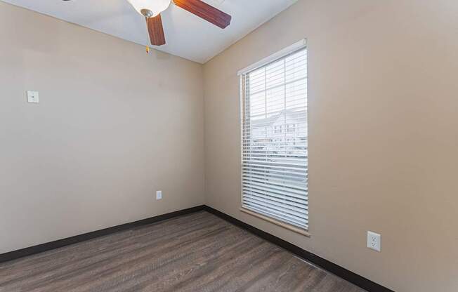 A room with a ceiling fan and a window with blinds