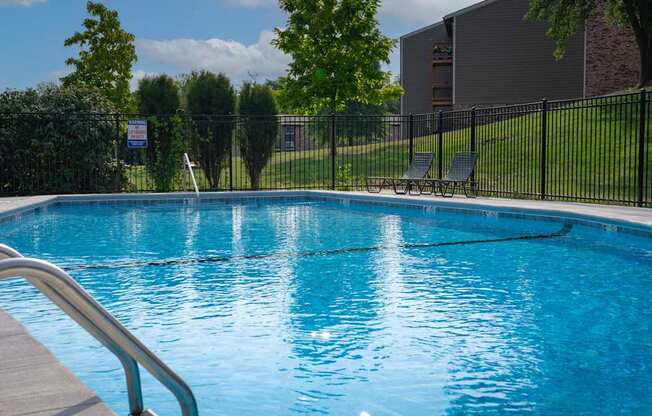 A pool with a metal railing in front of it.