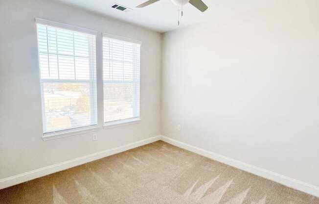 A room with a ceiling fan and carpeted floor.
