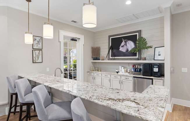 A kitchen with a marble countertop and grey chairs.