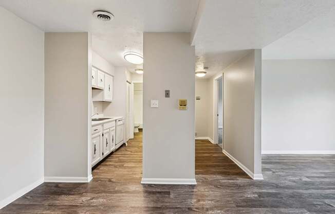 A long, narrow hallway with a kitchen area visible through the doorway.