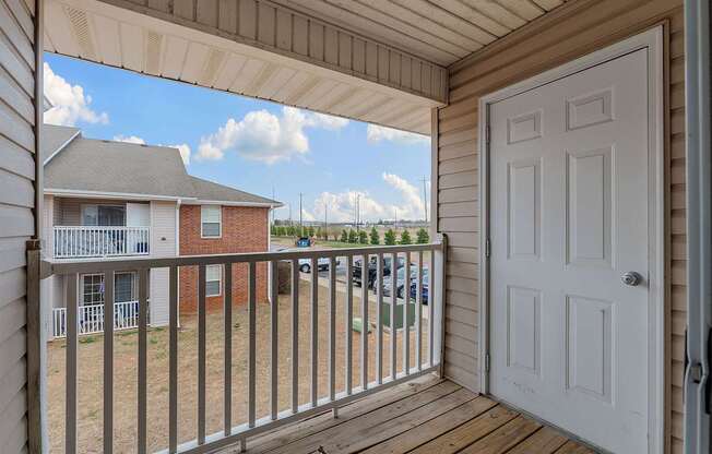 A white door is open to a deck with a railing.