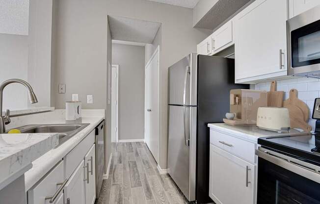 A kitchen with white cabinets and a black refrigerator.