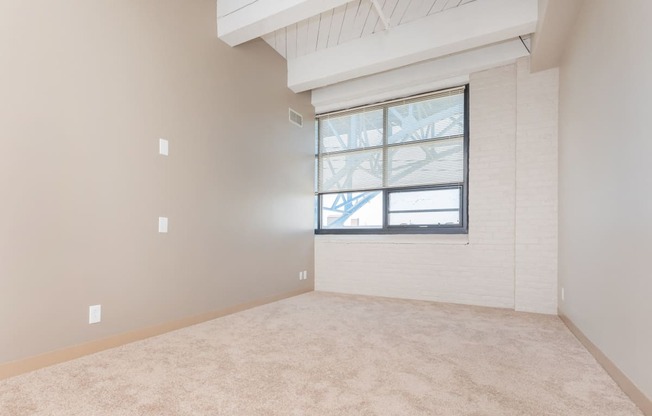 an empty living room with a window and carpet