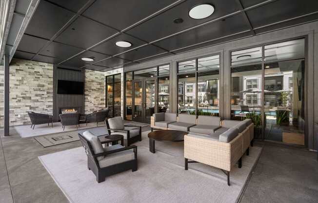 A modern outdoor seating area with a stone wall and glass doors.