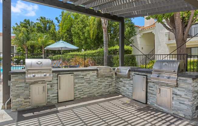 a patio with an outdoor kitchen with stainless steel appliances