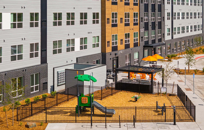 A playground with a green slide and a yellow umbrella.