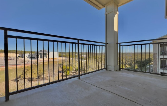 A balcony with a black railing and a concrete floor.