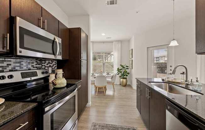 A modern kitchen with dark wood cabinets and stainless steel appliances.