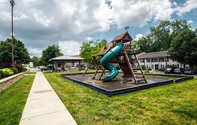 Apartments For Rent In Louisville, KY - Enclave At Breckenridge - Playground Surrounded By Grass with Concrete Walking Path Near Parking Lot And BBQ Area.