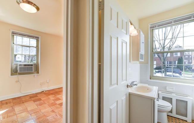 hallway view of living area and bathroom with large windows and hardwood flooring  at 1401 sheridan apartments in washington dc