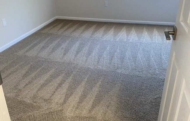 an empty room with a carpeted floor and a window