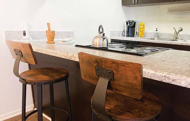 a kitchen with two stools in front of a counter