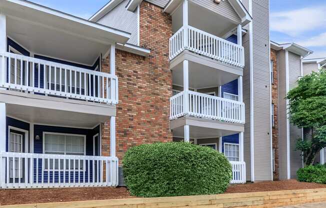 a building with two balconies and a bush in front of it at The Davis Apartments, Huntsville, AL 35816  