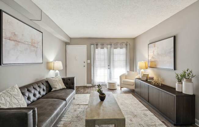A living room with a brown leather couch and a coffee table in the center.
