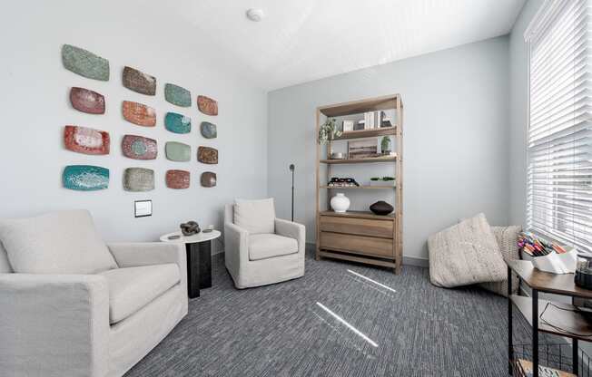 a living room with white couches and chairs and a table and a shelf with