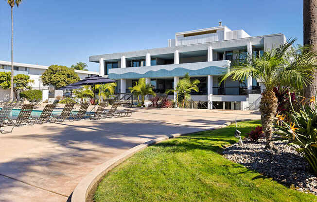 A modern building with a pool and palm trees in front.