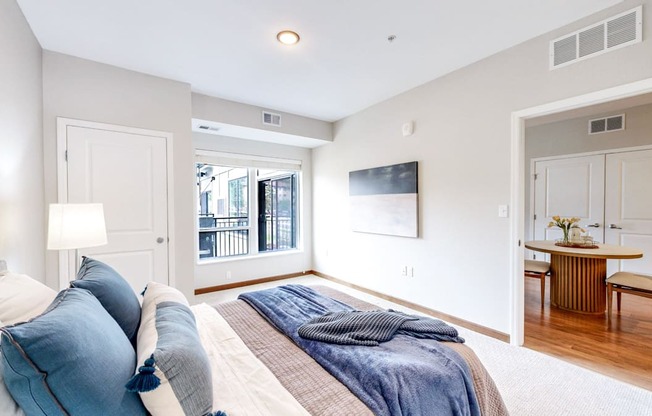 A bedroom with a large bed and a balcony outside.