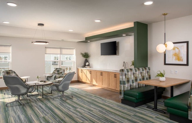 A modern office space with a green and grey carpet, a wooden table, and a television mounted on the wall.