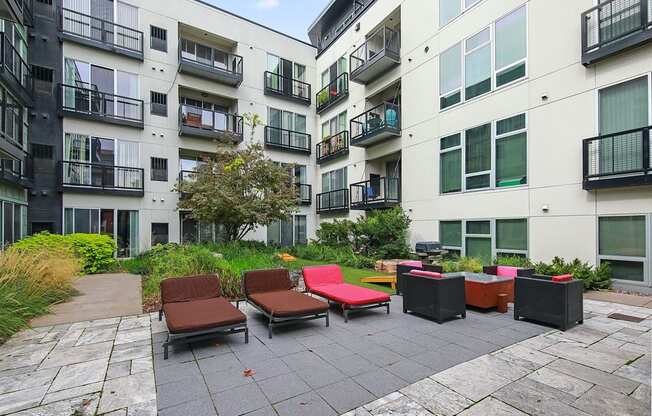 an outdoor area with lounge chairs in front of an apartment building