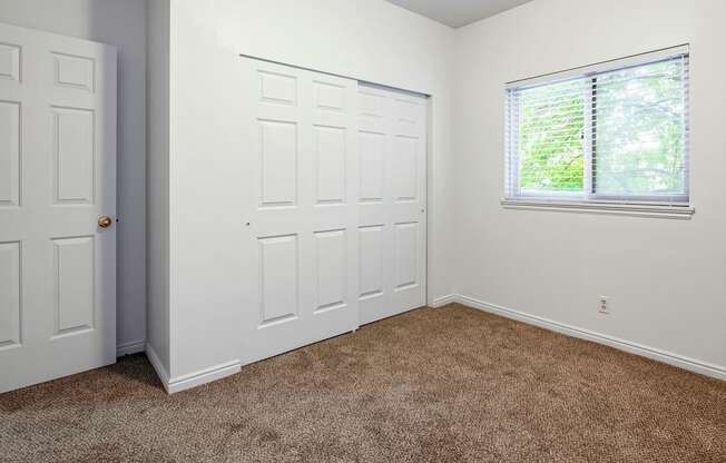 Bedroom with white walls, carpet flooring, a window, and a closet