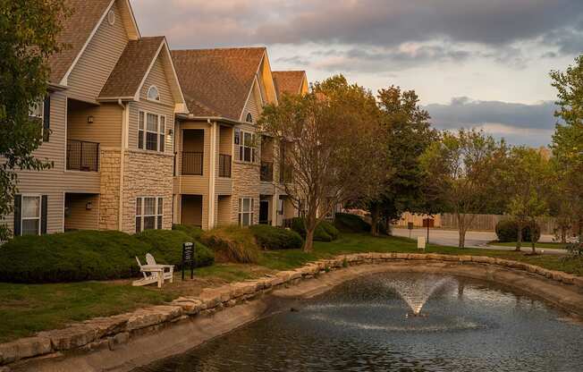a pond with a fountain in front of a building